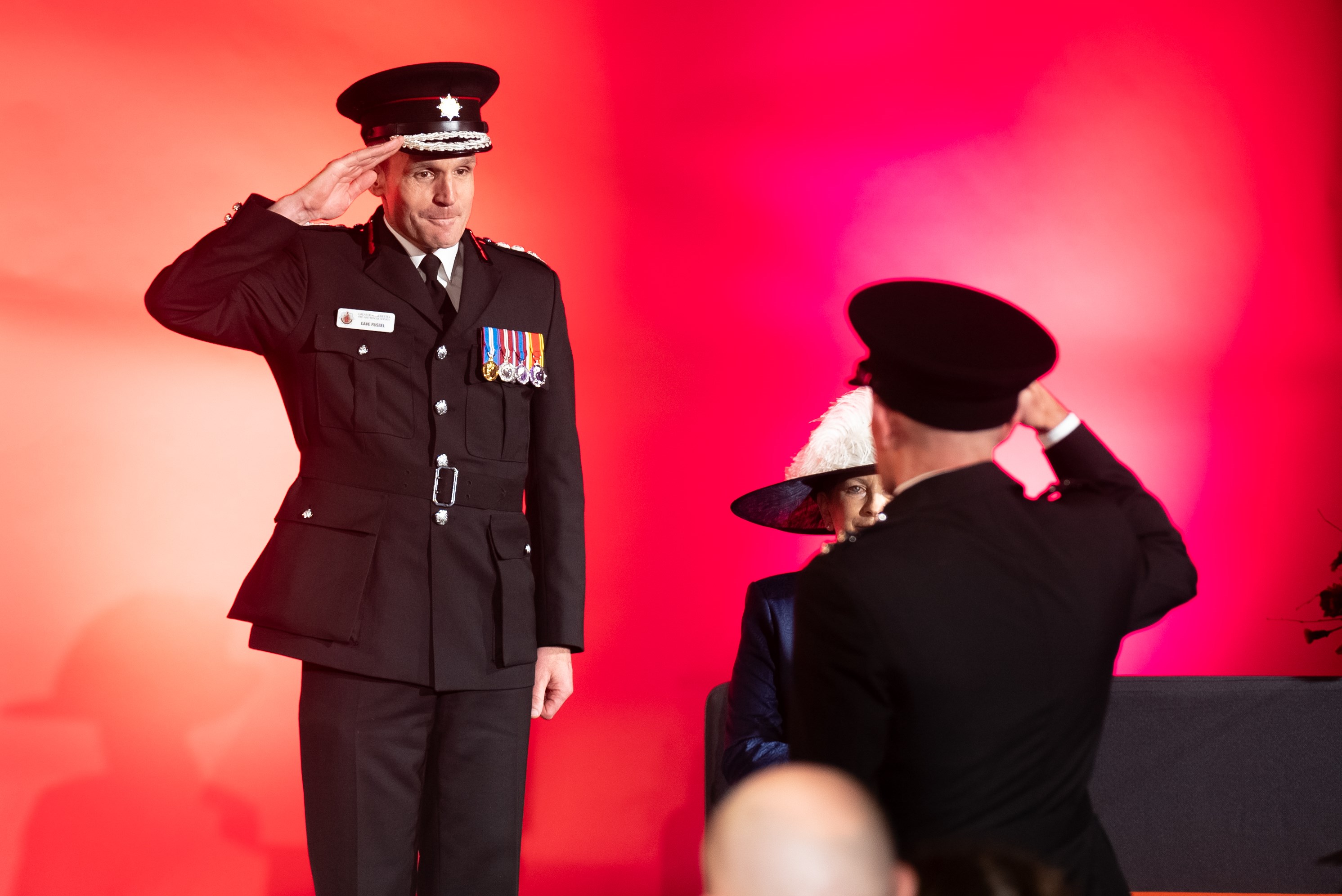 Chief Fire Officer, Dave Russel saluting an award recipient who is saluting back to him on stage at the Long Service Good Conduct award ceremonies.