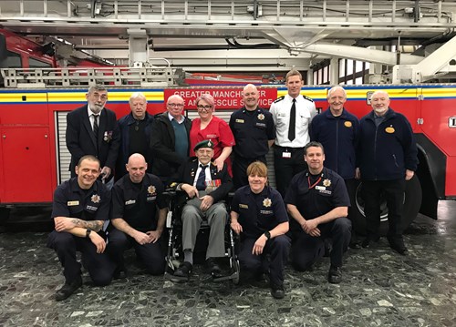 George in front of a fire engine with firefighters and officers at Whitehill Community Fire Station