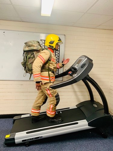 A firefighter on a treadmill wearing a backpack