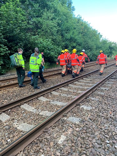 Emergency services carrying a stretcher along a railway track