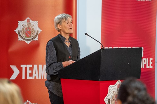 An image of Kate Green standing at a lectern in front of a GMFRS banner