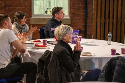 The Deputy Mayor and firefighters' family members sit around a table applauding