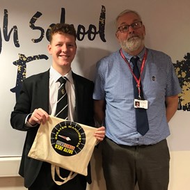 Competition Winner David Baker smiling and holding a Drive Safe tote bag standing next to a teacherteacher