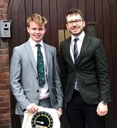 Competition Winner Patrick Wheeler and his teacher from Altrincham Grammar for Boys stood in front of door smiling