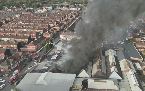 Rows of houses can be seen in the background of an image showing firefighters tackling a fire