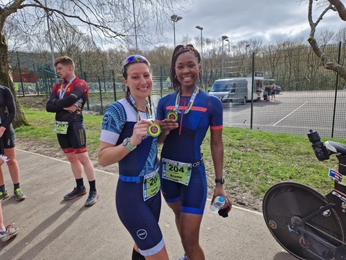 two women each holding medals won in triathlon competition.