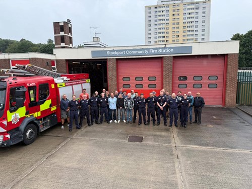 Stockport Community Fire Station pictured with all crew gathered in front. To the left is a fire engine.